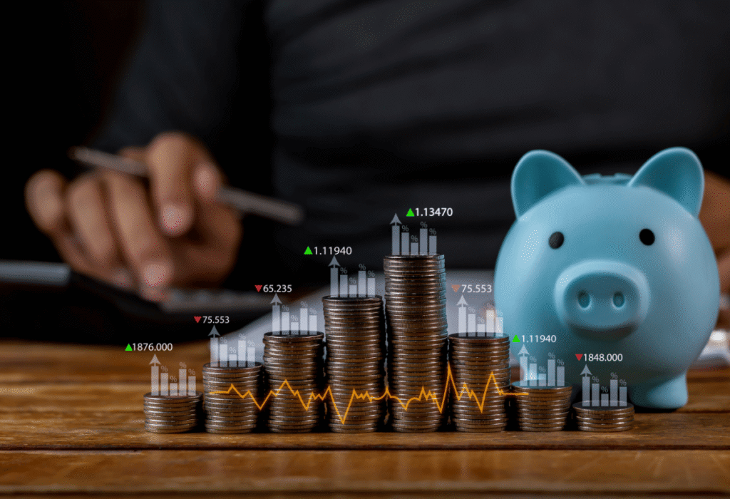 Pilhas de moedas em crescimento com gráfico financeiro e cofrinho ao lado, representando investimentos.