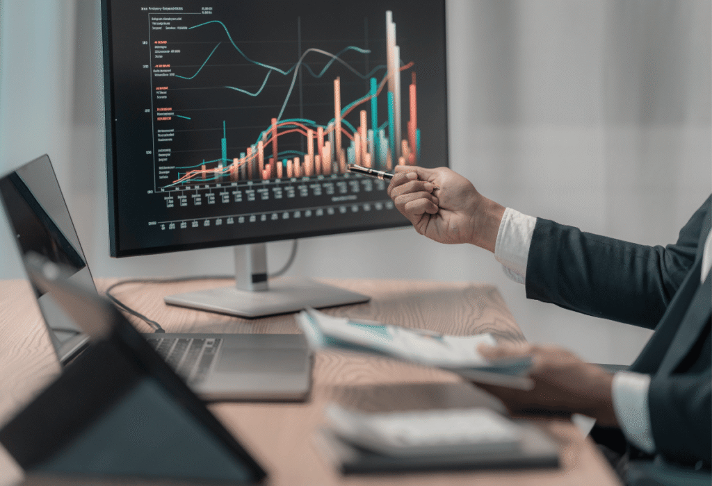 Profissional analisando gráficos financeiros em monitor durante atividade de assessoria de investimentos
